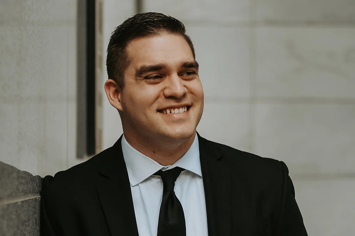 Young man smiling in black suit and tie