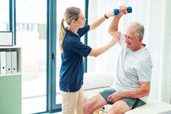 physical-therapist-assisting-senior-man-with-weights