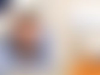 Man in blue shirt smiling, lying beside a small white dog indoors. Light background. "Wilsons Health" logo in corner with orange/blue colors.