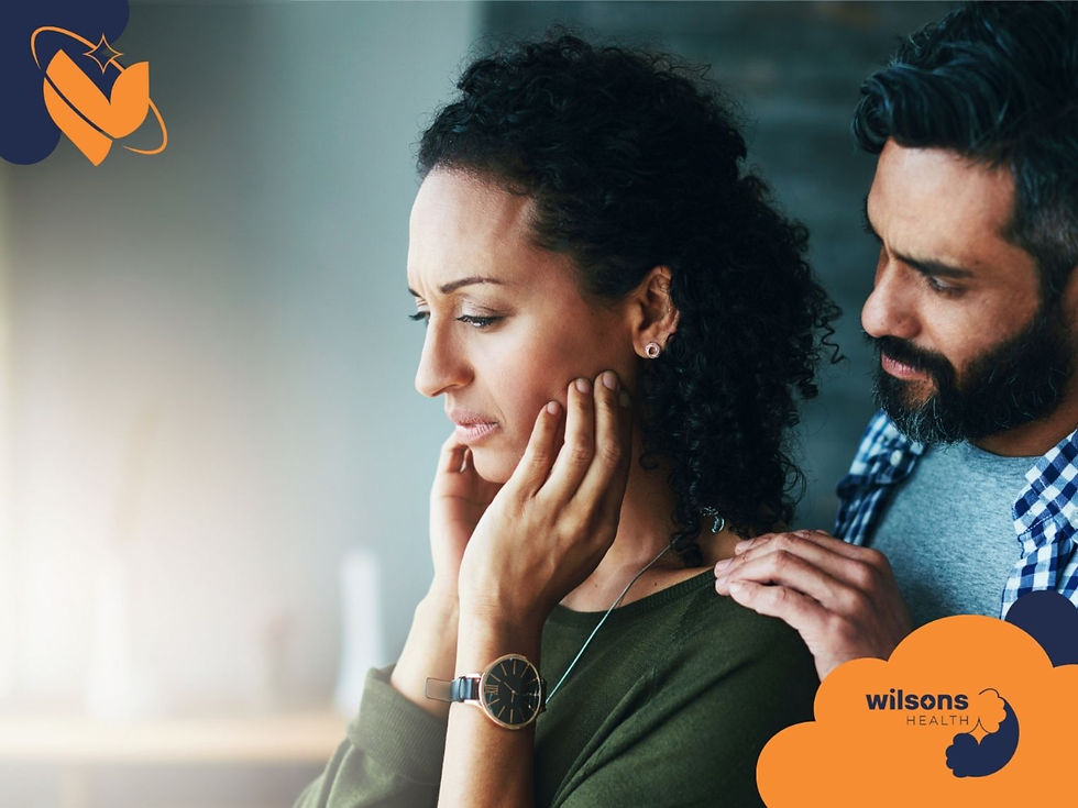 A thoughtful man comforts a worried woman indoors. She holds her face, his hand on her shoulder. Logos in corners say "Wilsons Health."