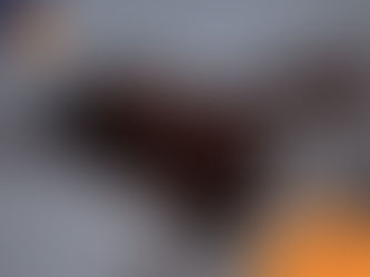 Person lying in bed with hands on face, appearing stressed. Gray and white bedding. Wilsons Health logo in orange at bottom right.