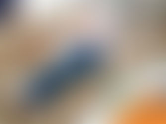 Elderly woman in white sweater and jeans happily cuddles a dog on a beige sofa. Cozy living room with patterned pillows and a table.