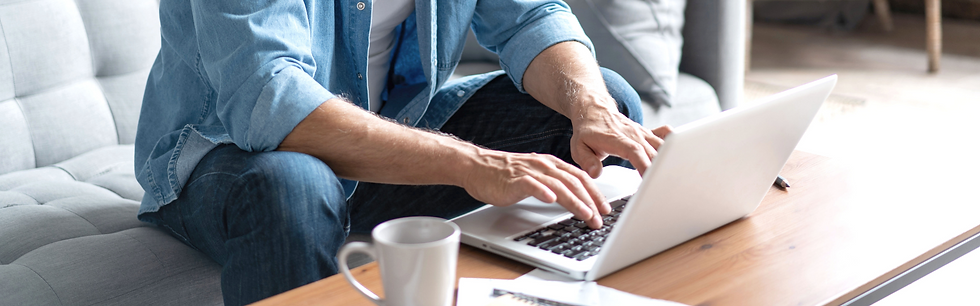 man on couch typing on laptop at the coffee table