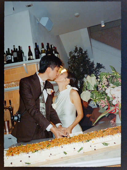 Long wedding cake with couple kissing and cutting cake