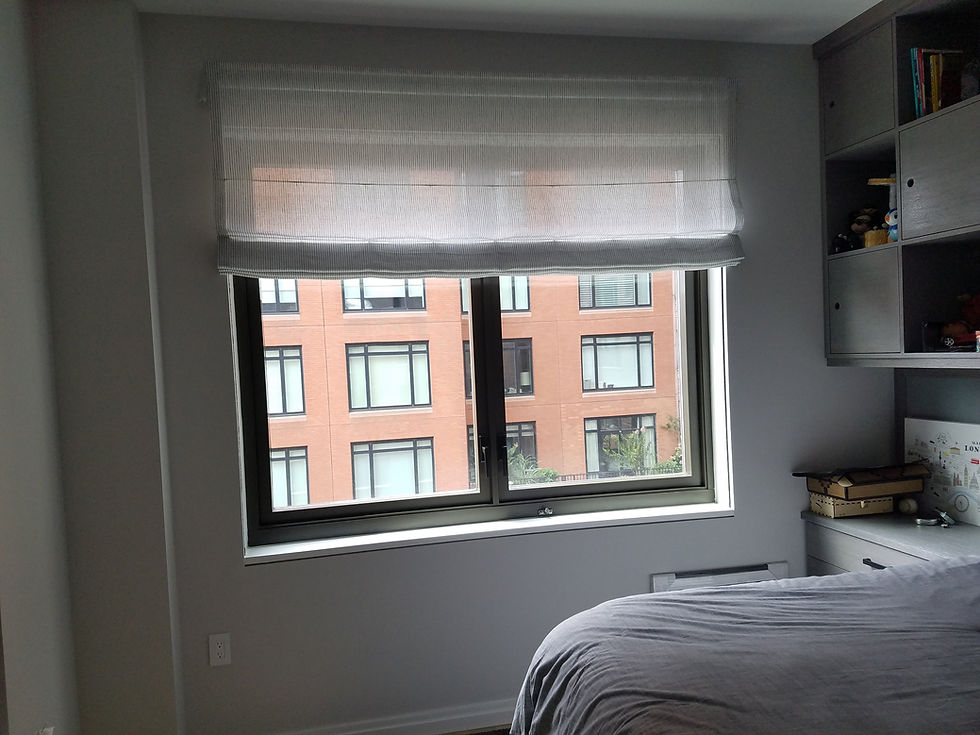 A cozy bedroom setup featuring modern motorized roller blinds, complemented by urban views through large windows, creating a sleek and convenient living space.