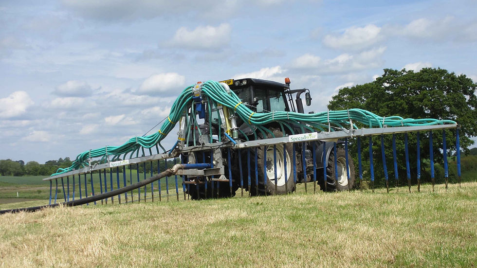 tractor pulling along a dribble bar across a field in the sunshine.