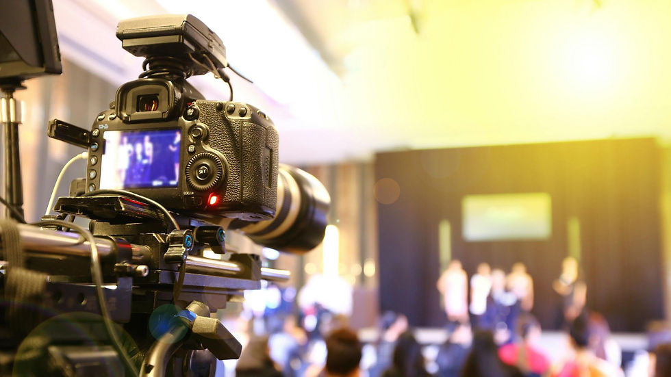 Professional video camera filming a presentation on stage at a corporate event.
