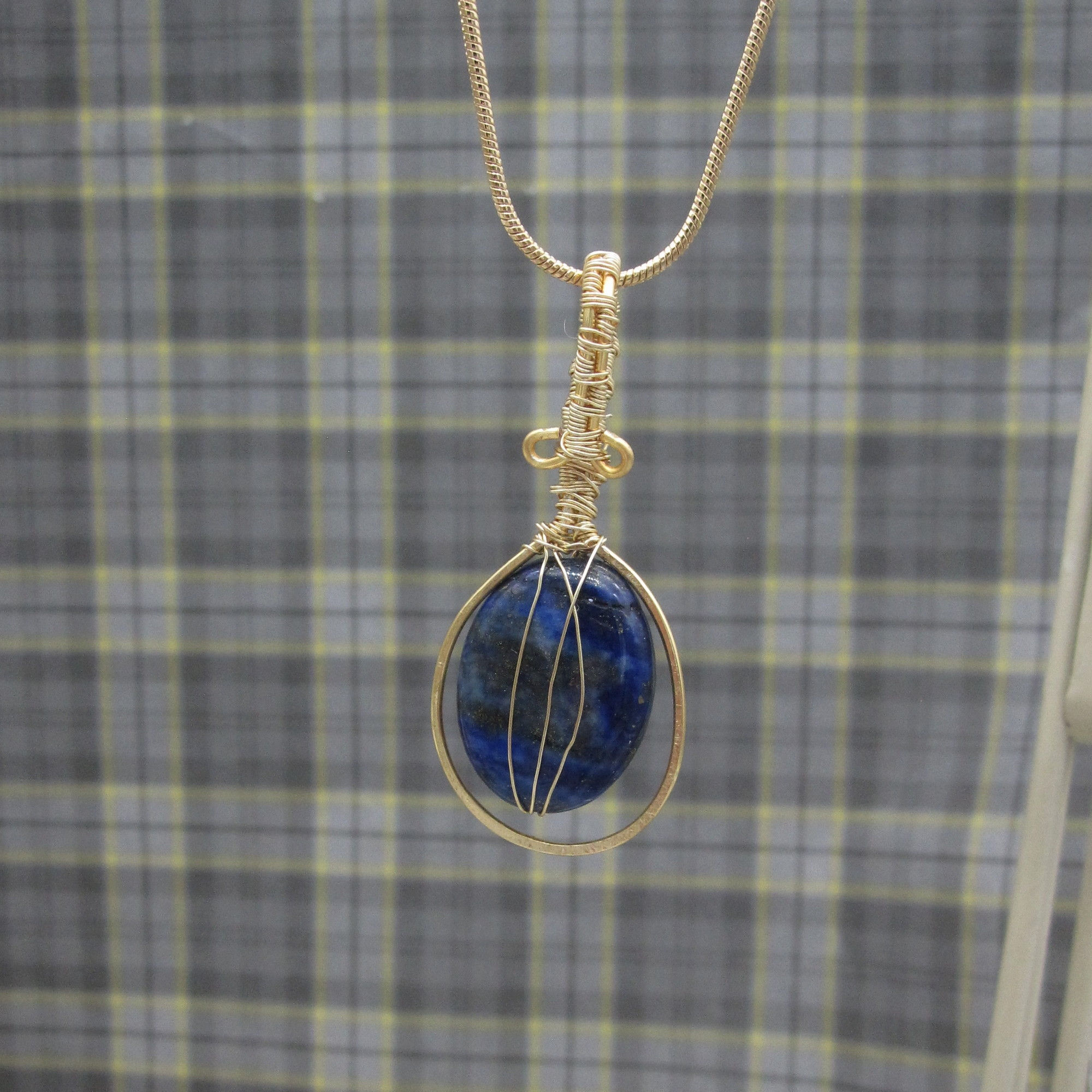 Pendant with oval lapis lazuli and wire wrapped bail on gold plated chain