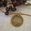 Thumbnail: Circular gemstone pendant, bright sunflower yellow with gold coloured wire wrapping. On leather cord.