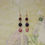 Thumbnail: Long drop earrings with three gemstones hanging one below the other. Two amethyst and one pink moonstone in a heart frame.