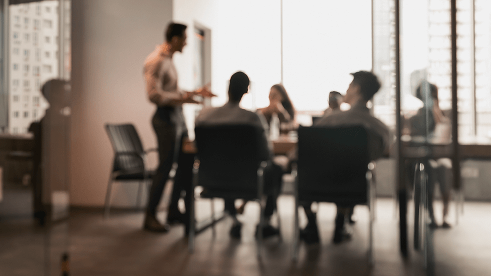 Group of executives talking in a meeting room; the image has a slight blur filter applied