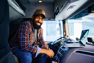 happy-black-truck-driver-using-laptop-and-looking-2024-01-30-00-31-32-utc.jpg