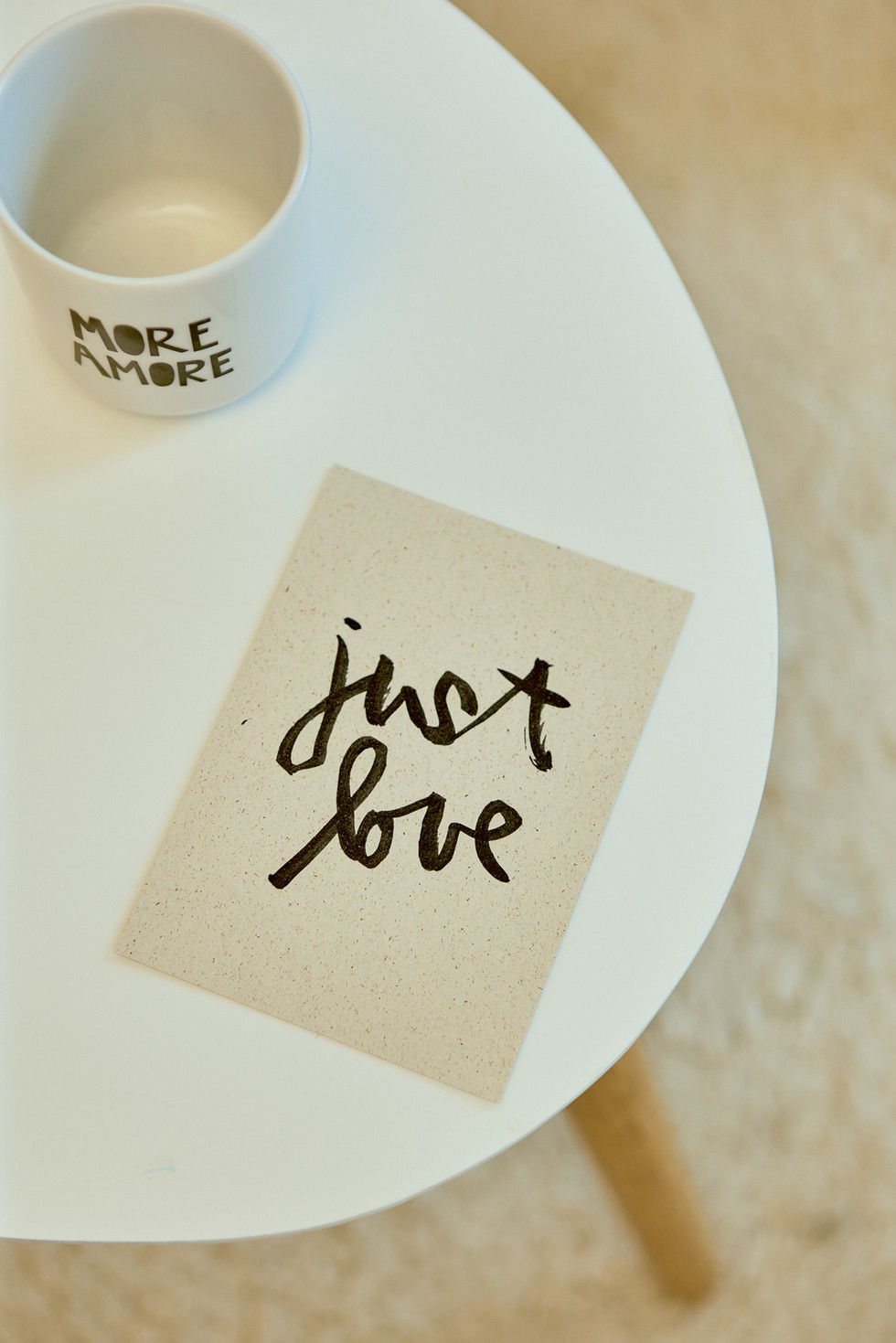 Ein Besietlltisch von oben fotografiert auf dem ein Becher steht und eine Karte liegt auf der just love steht