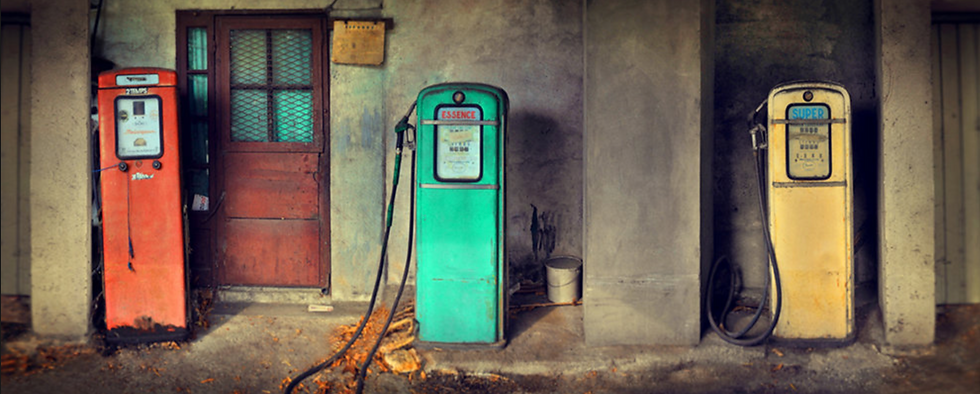 A photograph of three differently colored vintage gas station pumps.