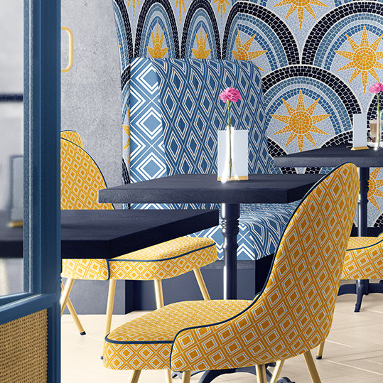 Mediterranean cafe with a blue and yellow sunburst mosaic wallpaper by Home Cyn Home and matching blue and yellow diamond pattern chairs and benches. 