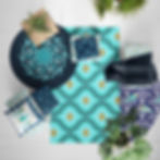 Flatlay decor featuring several blue and turquoise coastal themed rugs and pillows on a white wooden floor