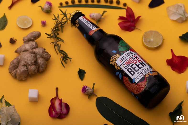 Top-down flat lay food styling of beer bottle with yellow background and spices.