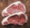 Two raw steaks placed side by side on a cutting table, ready for preparation.