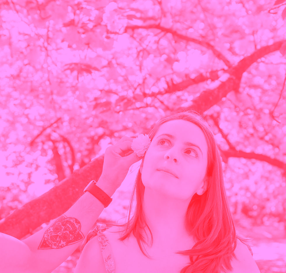 Jess Luszcz among cherry blossom trees. The photo has a pink filter.