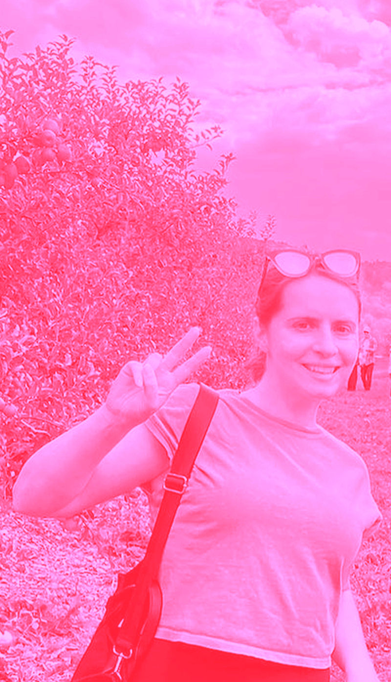 Jess Luszcz flashing a peace sign in a pink filtered photo.