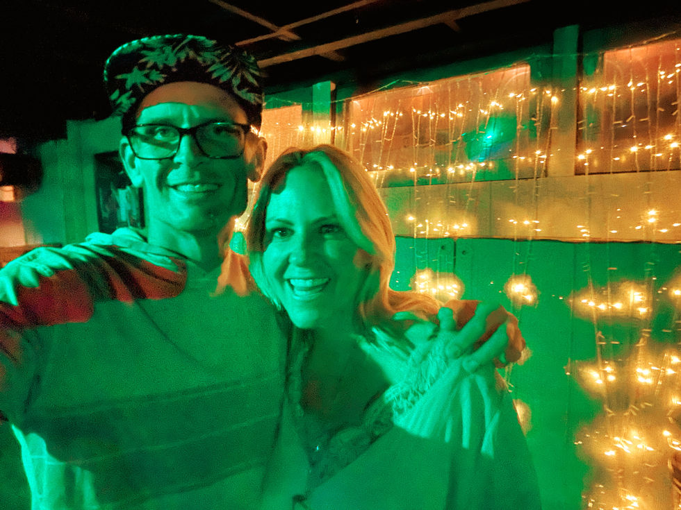 a man and a woman are posing for a picture with green lights behind them