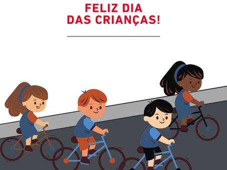 Desenho gráfico de 4 crianças andando de bicicleta em uma rua, e na parte de cima escrito "Feliz Dia das Crianças" e o logo da empresa Bicicletas Monark SA.