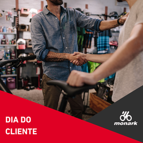 Post da Bicicletas Monark SA, mostrando dois homens apertando as mãos em loja de bicicletas; ao fundo, bikes e acessórios. Texto: DIA DO CLIENTE; elementos gráficos em vermelho e cinza e logo da Bicicletas Monark SA.