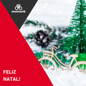 Brinquedo em madeira de bicicleta na neve com árvore de Natal ao fundo - na frente, elementos gráficos em cinza e vermelho com as escritas "Feliz Natal" e logo da empresa Bicicletas Monark SA em branco