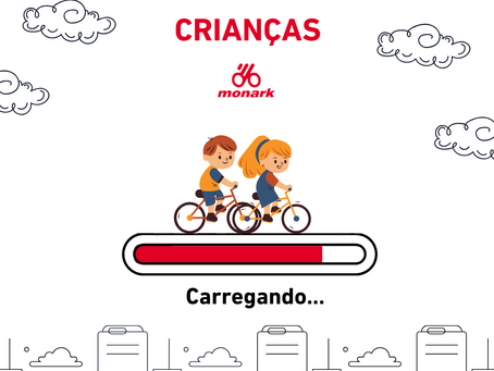 Post da Bicicletas Monark SA com ilustração do Dia das Crianças: duas crianças pedalam sobre barra de carregamento, com nuvens, logo Monark e texto "Carregando..." e cidade abaixo. No topo escrito "Dia das Crianças" e logo da empresa Bicicletas Monark SA