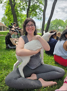a white woman sitting on the ground holding a goat.