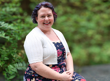 a white disabled woman with short brown hair wearing a white top and a colorful dress