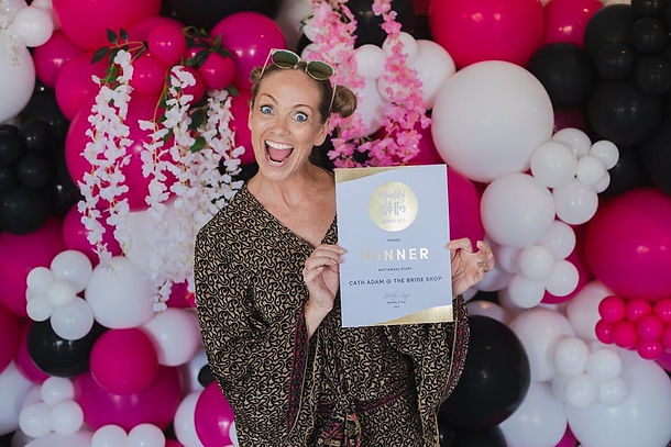 woman holds certificate in front of pink flowers and balloons