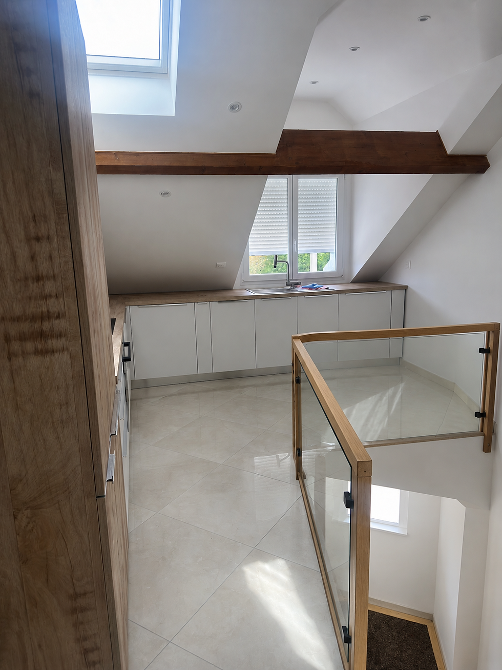 Cuisine contemporaine sous combles avec meubles sur mesure et poutre apparente.