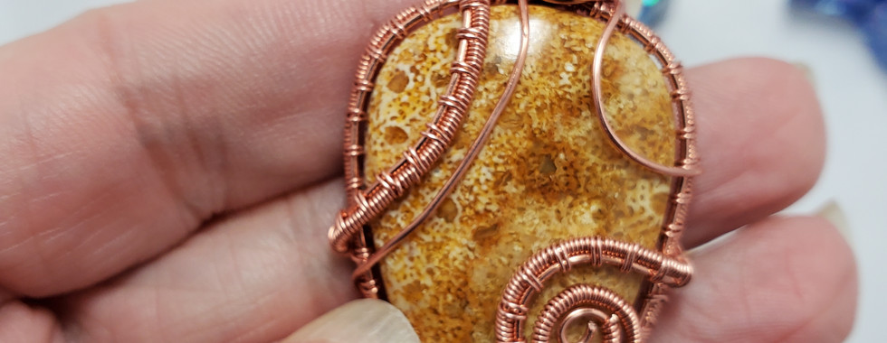 Hand holding copper wire-wrapped amber stone pendant