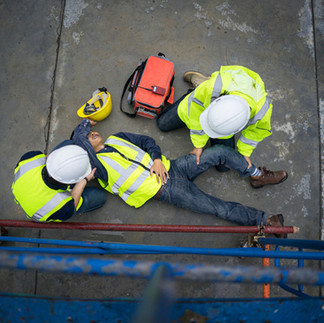 Emergency responders providing first aid care to an injured worker during a workplace incident scenario.