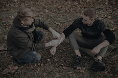 Community first aider applying a bandage to an injured person’s hand outdoors