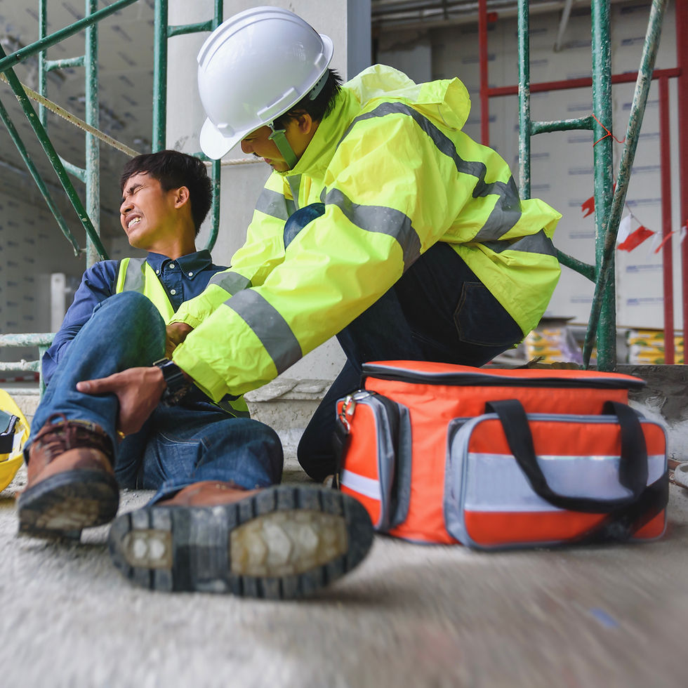 First aider supporting an injured construction worker beside a first aid kit
