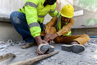 Workplace first aider assisting an injured construction worker during an emergency response scenario