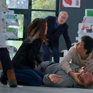 Colleagues assisting a person who has collapsed in a workplace environment, showing immediate first aid support.