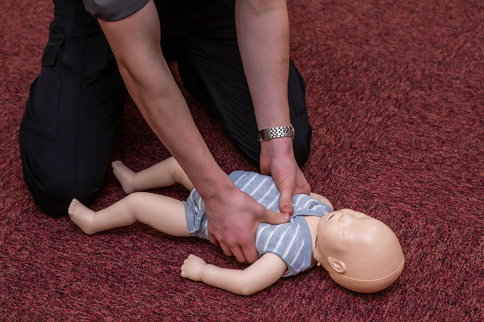 First aid trainer demonstrating CPR on an infant resuscitation manikin