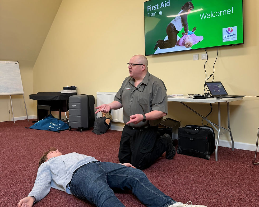First aid trainer demonstrating the recovery position with an adult casualty.
