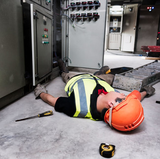 industrial accident worker laying on back whilst wearing workplace clothing after falling