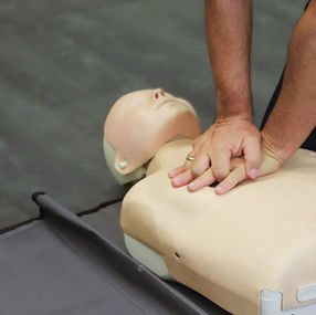 Close-up of chest compressions being performed on an adult CPR training manikin