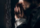 Man in dark clothing, hands clasped in prayer, leans close to a confessional grille. Dim lighting creates a solemn and contemplative mood.