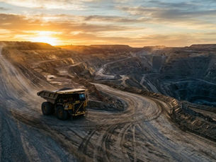 Autonomous haul truck stopped at a fork in an open-pit mine road at dawn, one path lit and one in shadow — illustrating the choice between open and closed autonomy architectures.