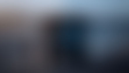 A person in a safety vest stands near a large autonomous truck in a quarry. Text "AUTONOMOUS" on truck. Horizon shows rugged terrain.