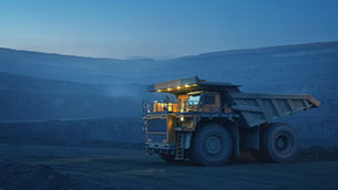 A single haul truck in an open-pit mine at dusk, representing where mining's Scope 3 emissions data chain begins under new GHG Protocol reporting rules.