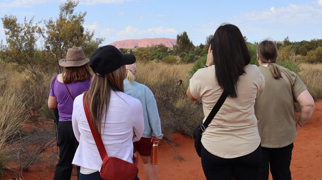 Uluru glowing red at sunset beneath a wide sky