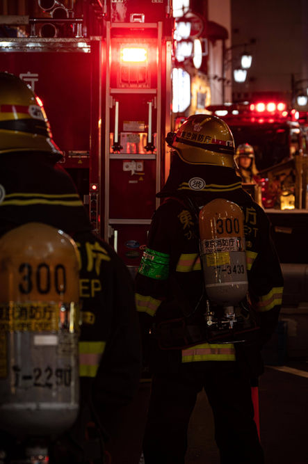 Tokyo firefighters stand ready, bathed in red emergency lights, capturing a moment of duty in the city’s night. - Thomas Oberdorfer Photography
