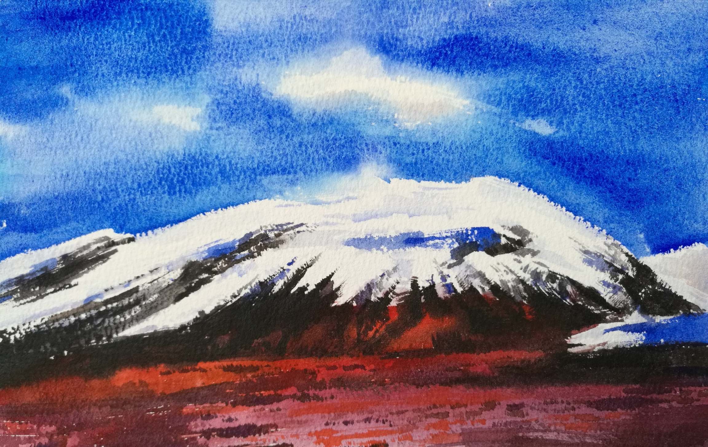 red ground and brown snow covered mountain with bright deep blue sky and some white clouds